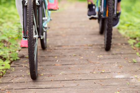 Close up of front wheels of bicycles. Man and woman are traveling in parkの写真素材