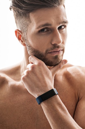 Fit young man is thinking about something seriously. His torso is naked. Athlete is looking at camera pensively. Isolatedの写真素材