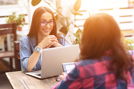 They have wifi zone. Shot of two friends sitting together in cafe while using digital tablet and laptopの写真素材