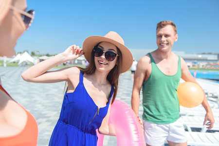 Happy young friends are enjoying summer. They are standing near swimming pool and smilingの写真素材