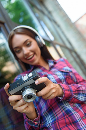 Carefree girl is photographing something with interest. She is enjoying music from headphones and smiling. Focus on cameraの写真素材