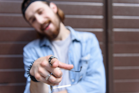 I choose you. Self-sufficient young man is pointing finger at camera with confidence. He is standing and smilingの写真素材