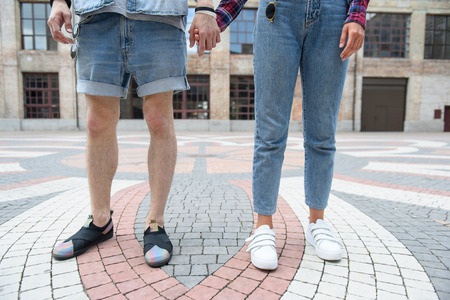 Close up of legs of loving couple holding hands. They are standing on street