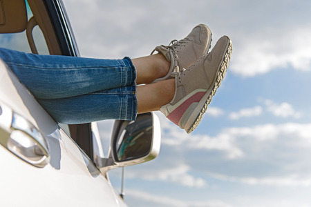 Time to relax. Close up of woman legs out window in car above clouds