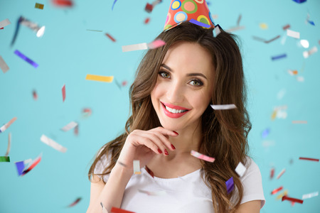 Carefree girl is celebrating her birthday. She is standing and wearing party cone. Lady is smiling. Isolatedの写真素材