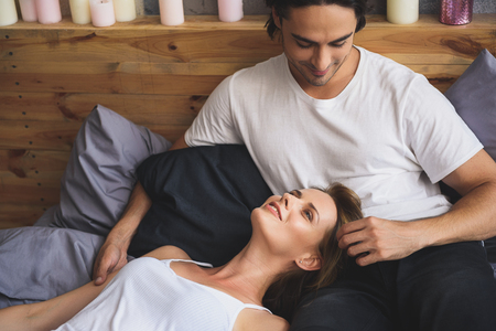 girl lying on a bad with boyfriend while he touching her hairの写真素材