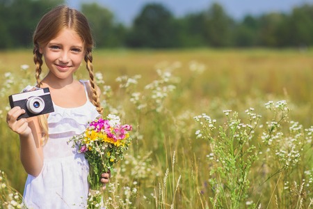 I like photographing nature. Happy girl is holding camera and taking shots. She is standing on...
