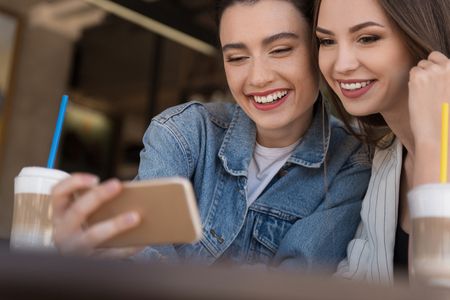 women holding a smartphone and smiling with teethの写真素材