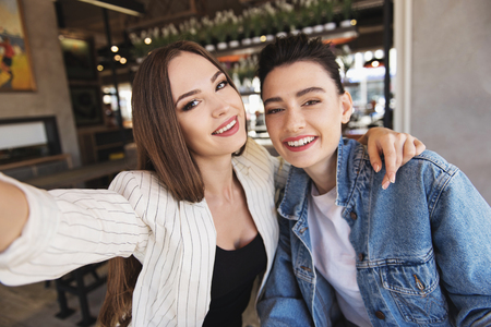 cheerful young women taking a selfie in a boutiqueの写真素材