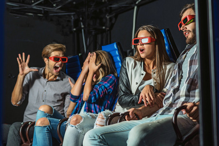 man scaring her girlfriend and friends in movie theater