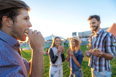 selective focus on man with hamburger in front of his friends