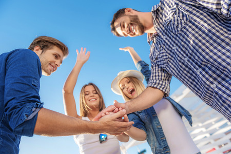 teamwork and success concept, group of four holding handsの写真素材