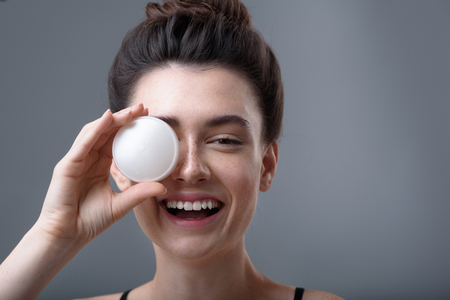 skin care concept, close up of a young happy girl holding cosmetic jarの写真素材