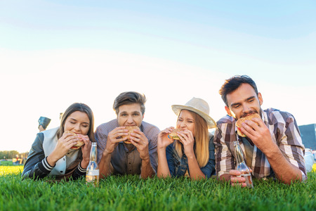 friendship and summer concept, friends eating in the park with copy spaceの写真素材