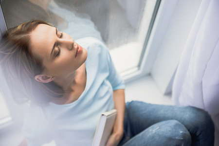 beautiful lady sitting with book with closed eyes, fall blues conceptの写真素材