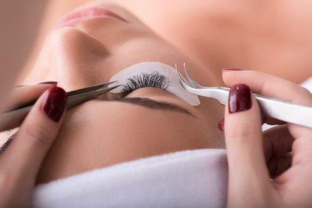 Want to know my secret. Close up of woman eye with long eyelashes during correction procedure in...