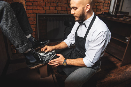 bearded professional artisan washing brogues with a sponge, close upの写真素材