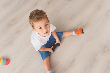 Top view photo of small boy holding console in his hands and looking into camera