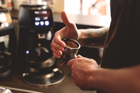 barista holding a ground coffee in a portafilter, close up, selective focusの写真素材