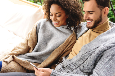 handsome man with his wife listening to music while sitting on a couchの写真素材