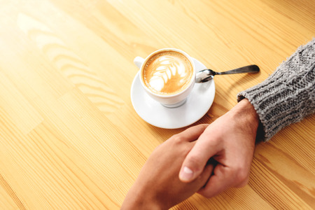 romantic date concept, man holding the hand of a woman on the wooden tableの写真素材