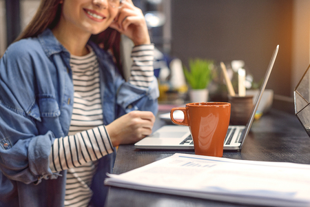 Loving free wifi. Cropped photo of smiling woman enjoying cup of coffee with her laptop open in front of herの写真素材