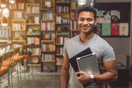 Library always has what I need. Cropped portrait of young male college student staing in library and holding digital tabletの写真素材