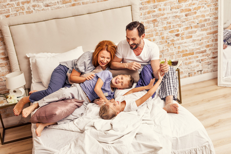 happy parents laughing and having fun while playing with their cute children at homeの写真素材