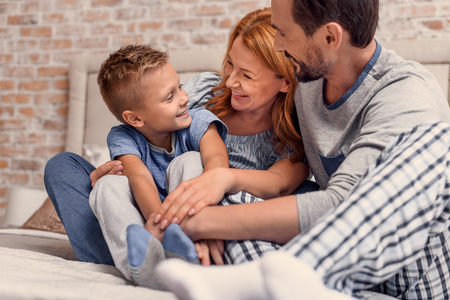 Cropped shot of smiling parents and their little son spending morning time in bed togetherの写真素材