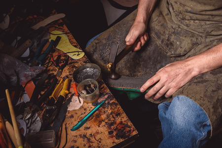 repairing of a shoe with a hammer by a cobbler at the workplaceの写真素材