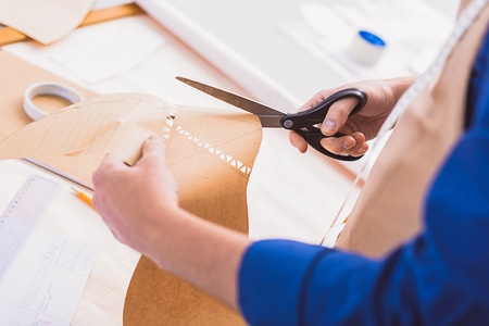 cutting shape of a new shoe on a yellow paper indoors