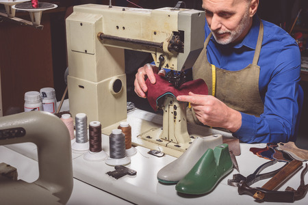 cobbler stitching parts of a shoe in one piece on tailoring machineの写真素材