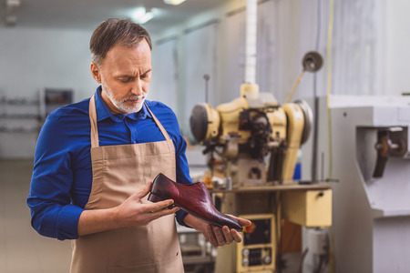 owner of a small workshop making business looking at shoeの写真素材