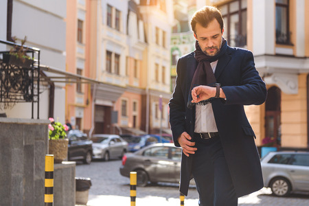 Businessman is going in city and looking at watch with concentrationの写真素材