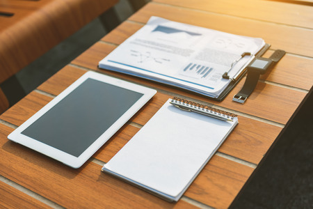 Close-up of notebook, tablet, smartwatch and financial papers on desk in cafeの写真素材