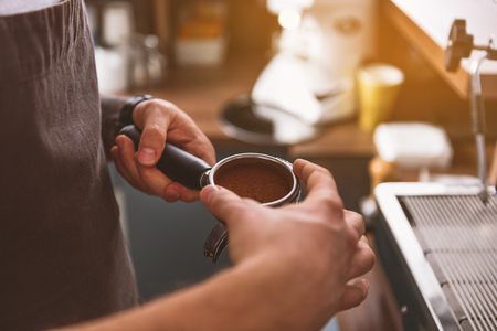 employee of a coffee shop holding portafilter with beans, close upの写真素材