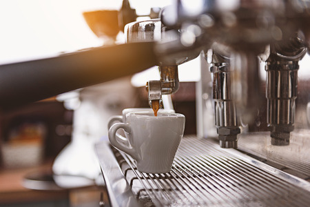 fresh coffee pouring into a small white cup, side view, selective focusの写真素材