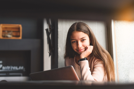 Hilarious teenager female is sitting and using laptopの写真素材