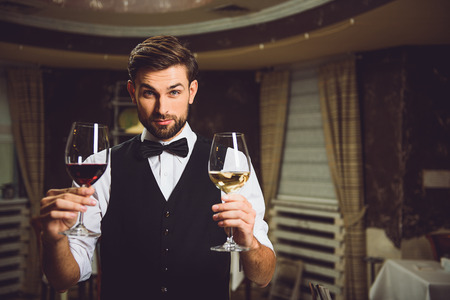 Wine expert is showing goblets with red and white beverage and smilingの写真素材