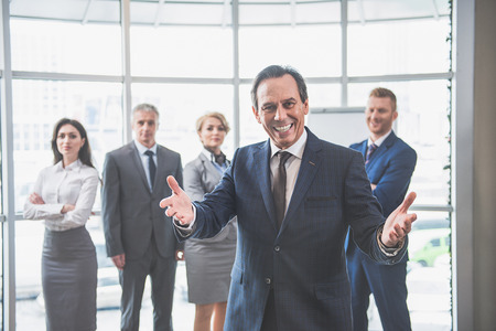 Welcome to our team. Focus on boss who is standing with his hands widely open and smiling