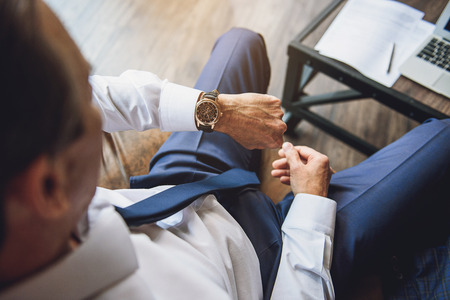 Mature male businessperson is sitting and checking time. Top view