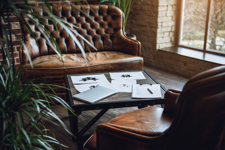 Room with furniture. There are rorschach test, laptop and paper on tableの写真素材