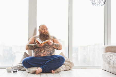Mature fatso entertaining with literature in apartmentの写真素材