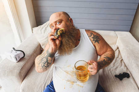 Drunk fat man eating unhealthy foodの写真素材