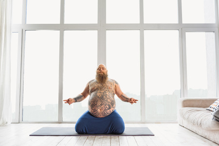 Relaxed thick guy meditating at homeの写真素材