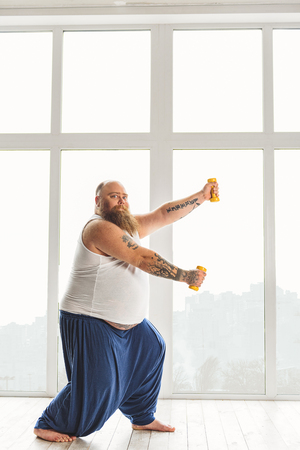 Bearded fat man doing exercise with dumbbellsの写真素材