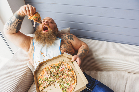 Hungry fat man eating unhealthy foodの写真素材