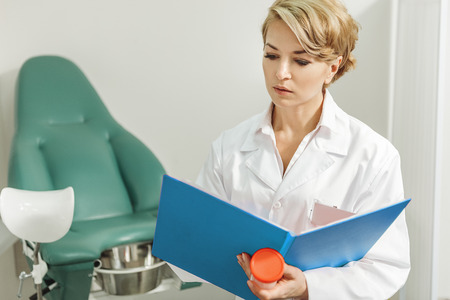 Concentrated female doctor looking through informationの写真素材