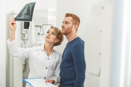 Serious female physician in cabinet with x-ray apparatus
