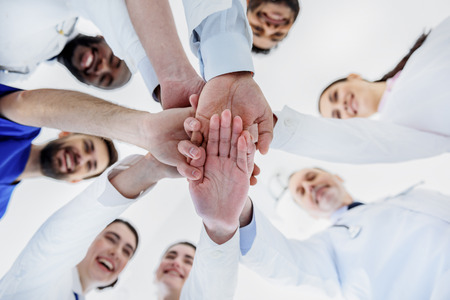 Happy general practitioners putting arms togetherの写真素材